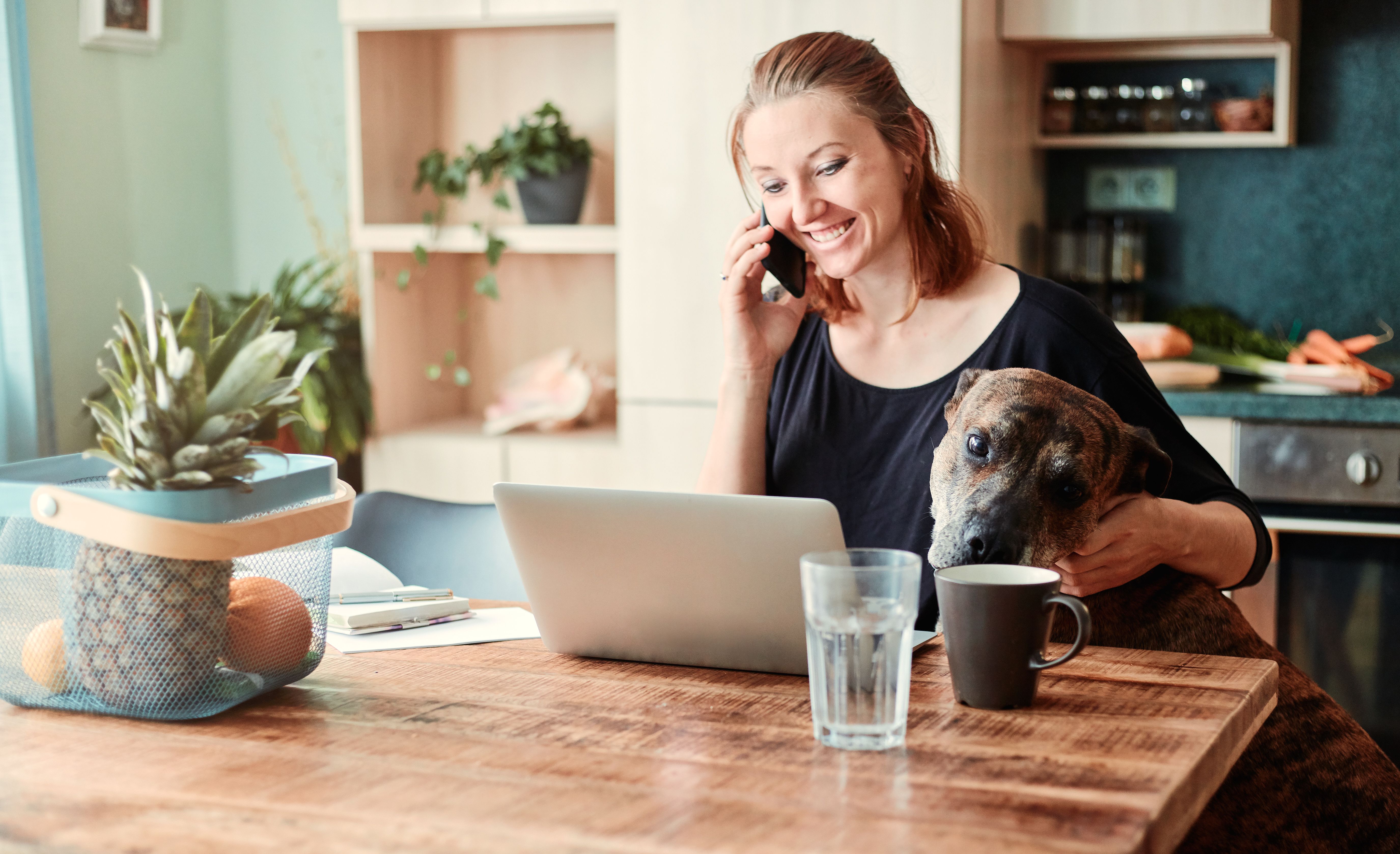 Woman working on a laptop at a kitchen table
